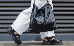 image of woman wearing white pants, a black tote bag, and black platform fisherman sandals