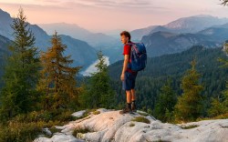 Hiker at the summit of Feldkogel, mountain landscape, view of Koenigssee at sunset, left Watzmann Suedspitze and Watzmannkinder, Berchtesgaden National Park, Berchtesgadener Land, Upper Bavaria, Bavaria, GermanyVARIOUS